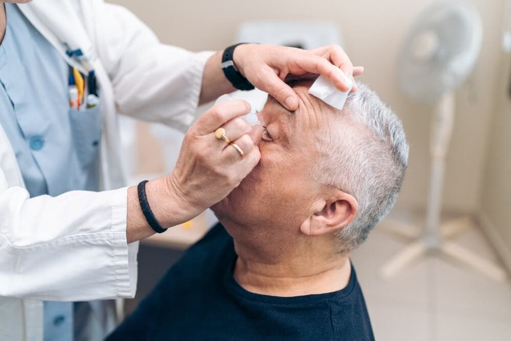 Vor und Nachteile einer Augenlaser Behandlung, Augentropfen werden Mann verabreicht