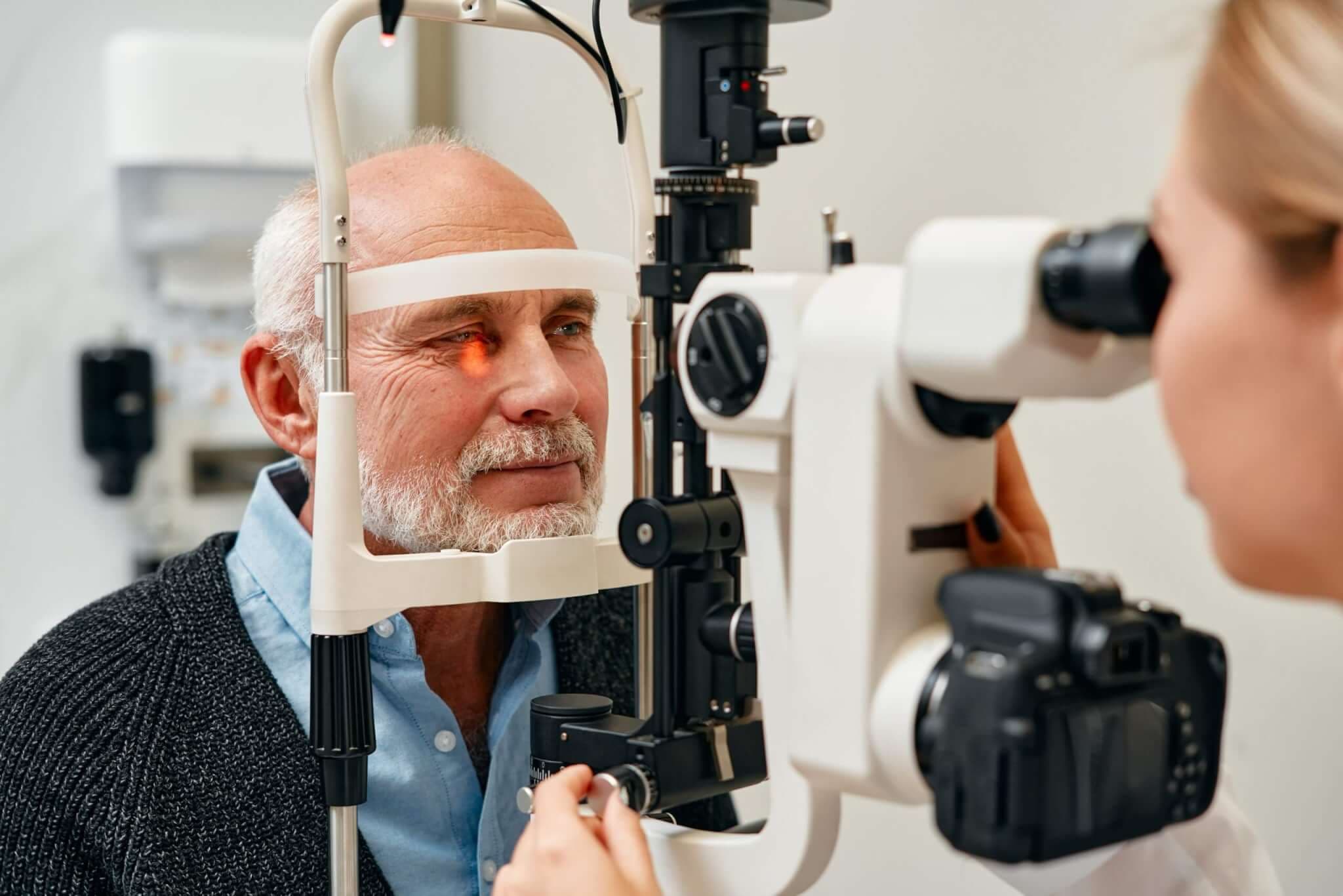 Älterer Mann bei Augenuntersuchung mit Spaltlampe im Optikerzentrum.