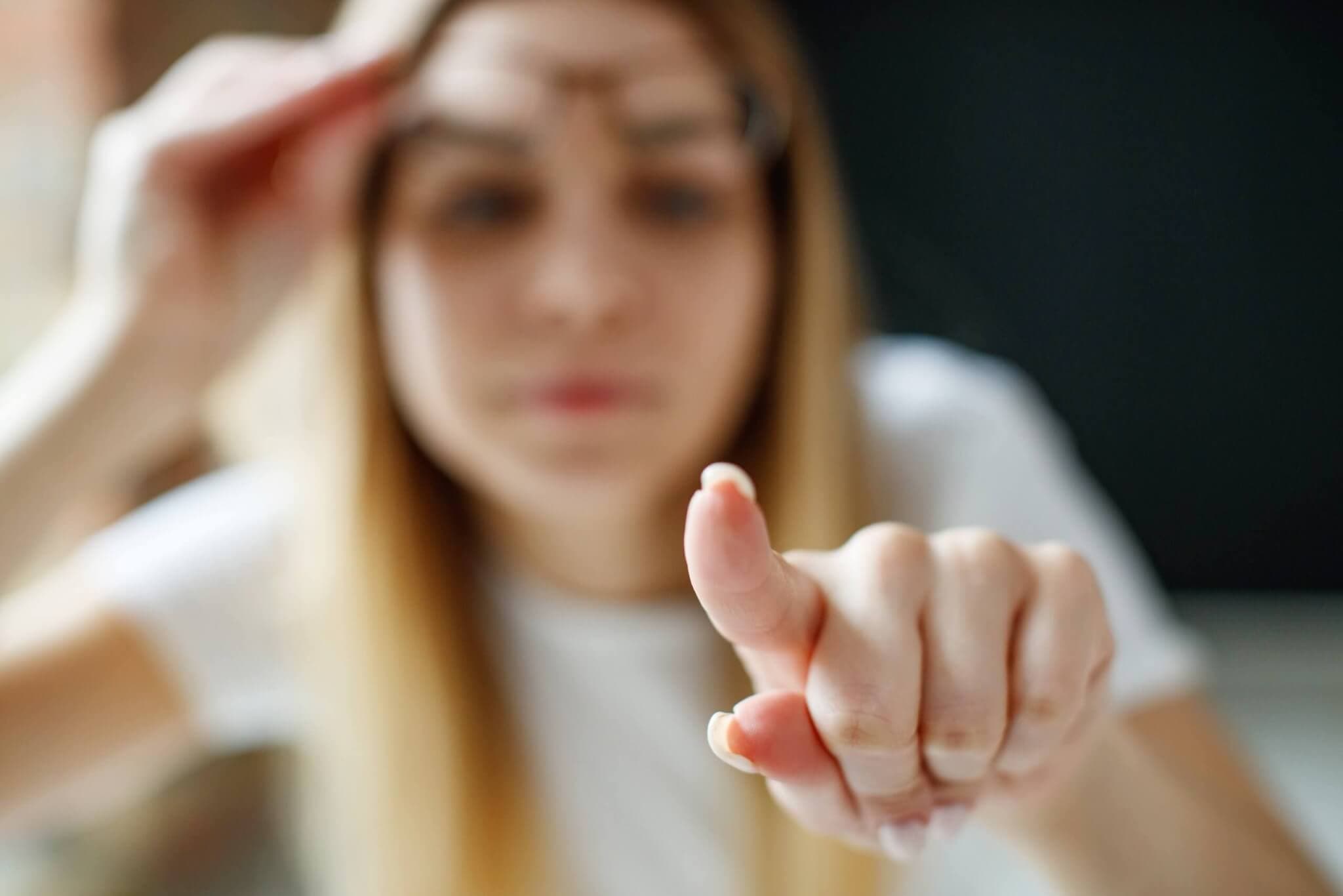 Weitsichtigkeit, Hyeropie einfach erklärt. frau die mit dem Finger auf die Linse drückt und die Brille hochhebt, wobei die Frau verschwommen ist.