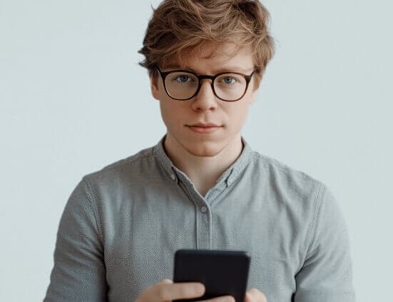 Junger Mann mit Kurzsichtigkeit informiert sich über Augenlasern Smartphone