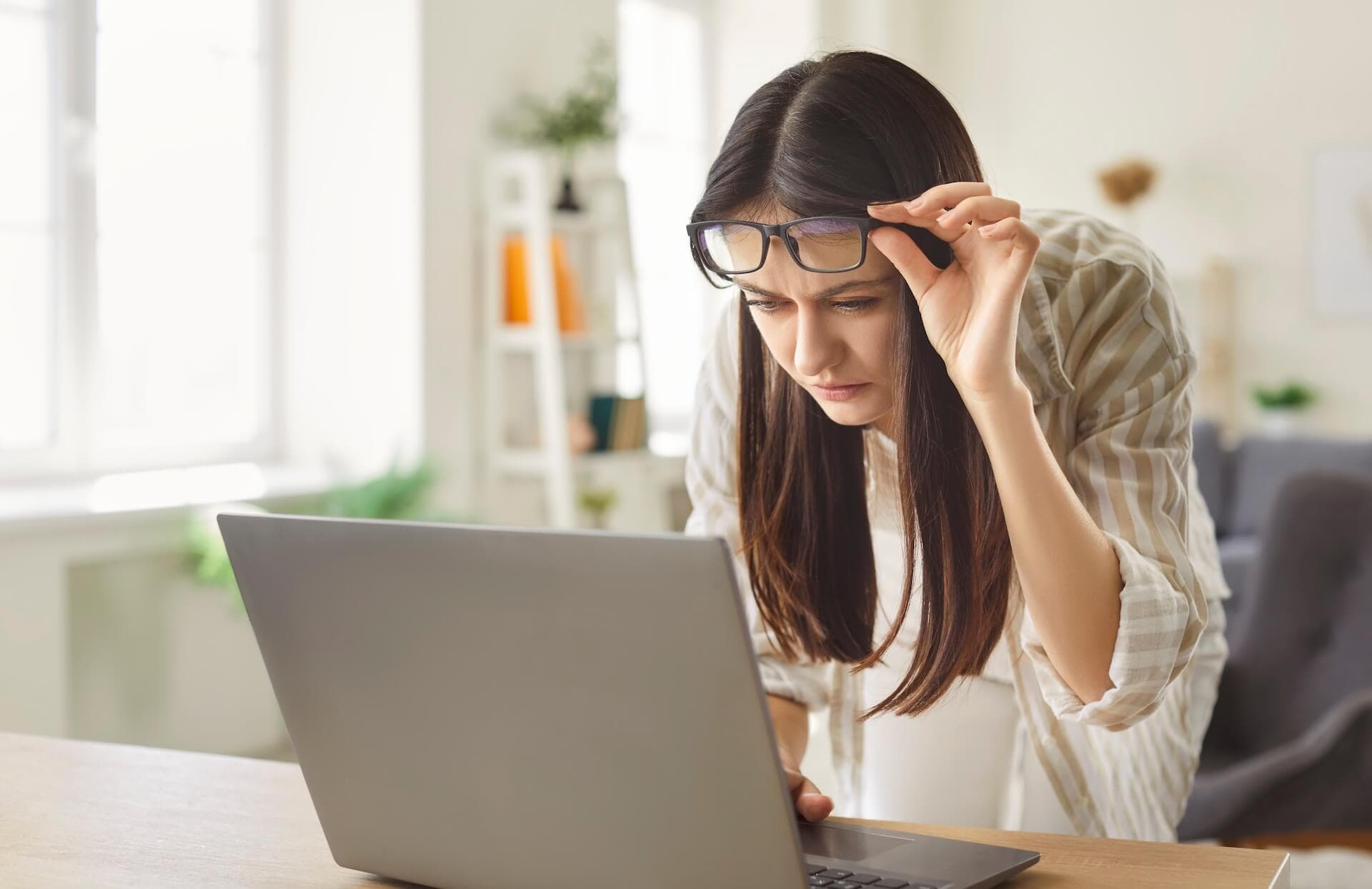 Frau sieht verschwommen auf ihrem Laptop aufgrund einer Hornhautverkrümmung.