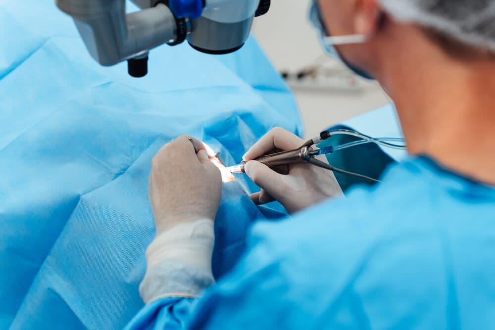 Chirurg bei einer Augenoperation mit Mikroskop und chirurgischen Instrumenten.